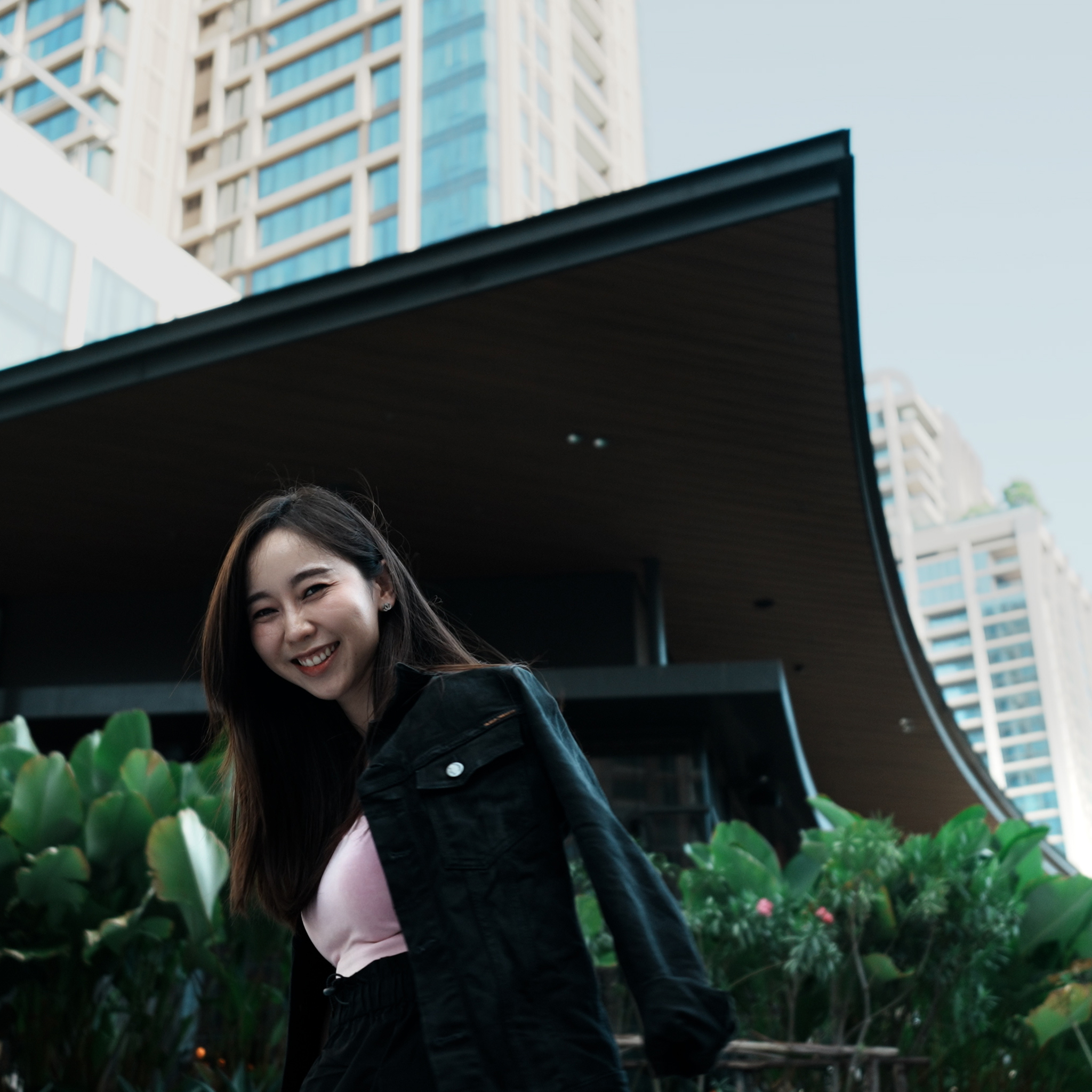 Side view of girl with black jacket, captured from a lower angle, with buildings in the background